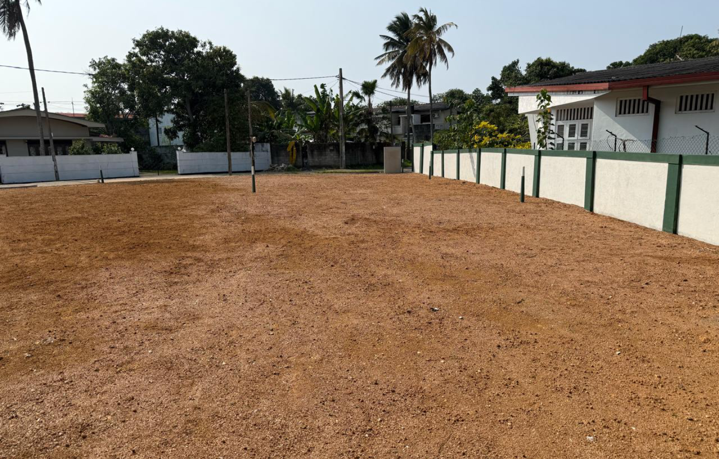 Cleared residential plot with boundary walls and dry soil