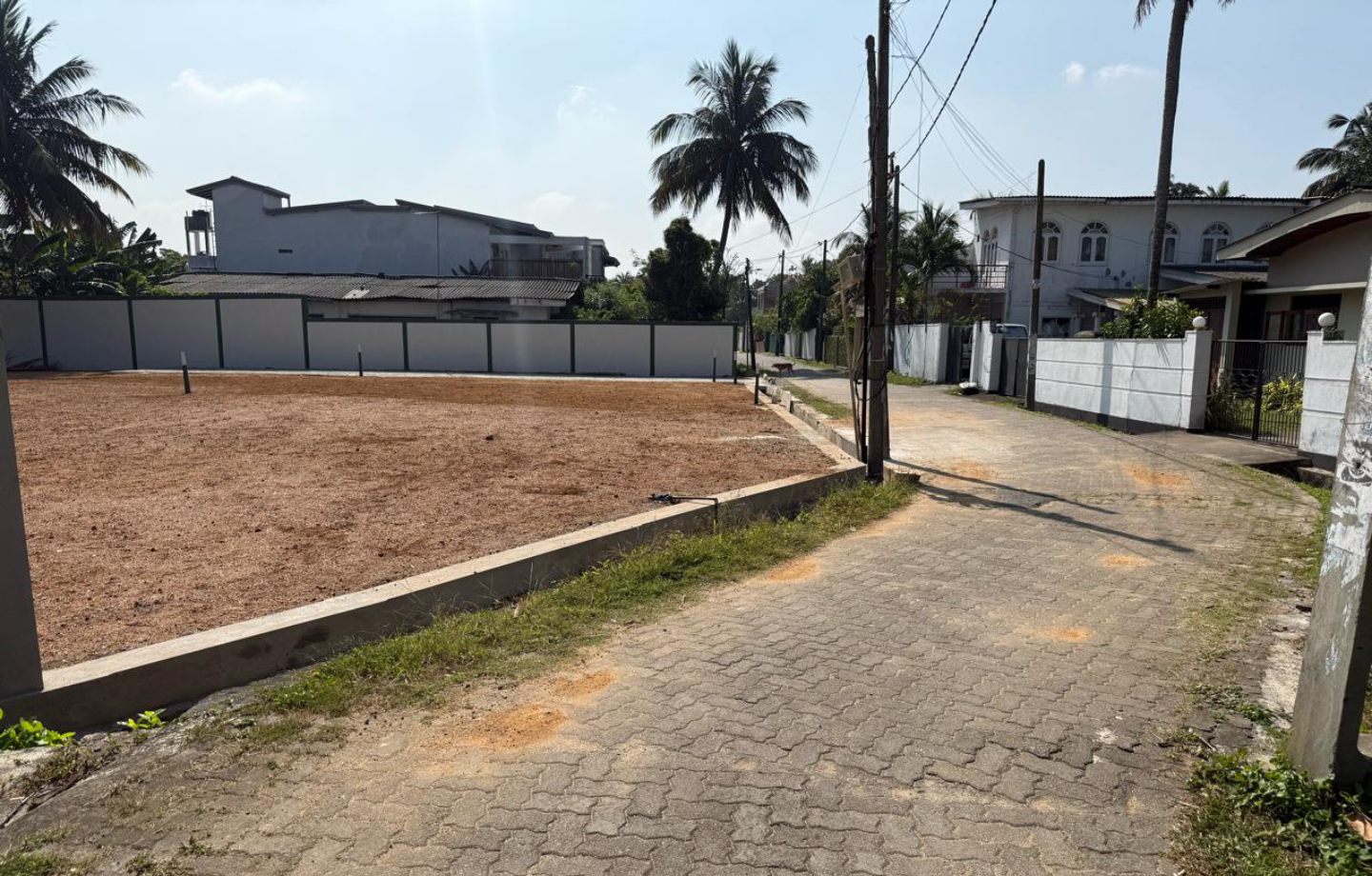 Paved driveway leading to an open plot