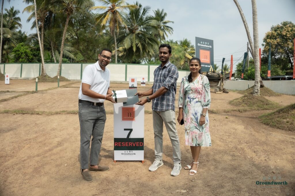 Three people at a ground-breaking ceremony holding a project sign